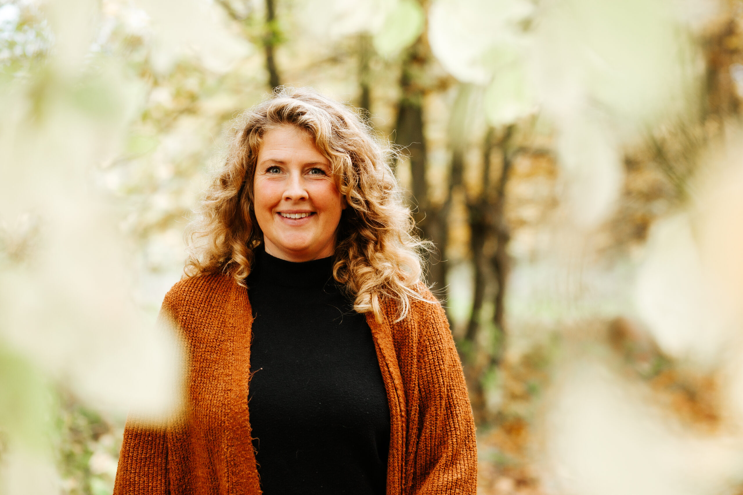 Stefanie Schmidt lächelt an einem sonnigen Herbsttag im Wald in die Kamera